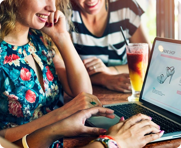 Two women sitting at a table with laptops.